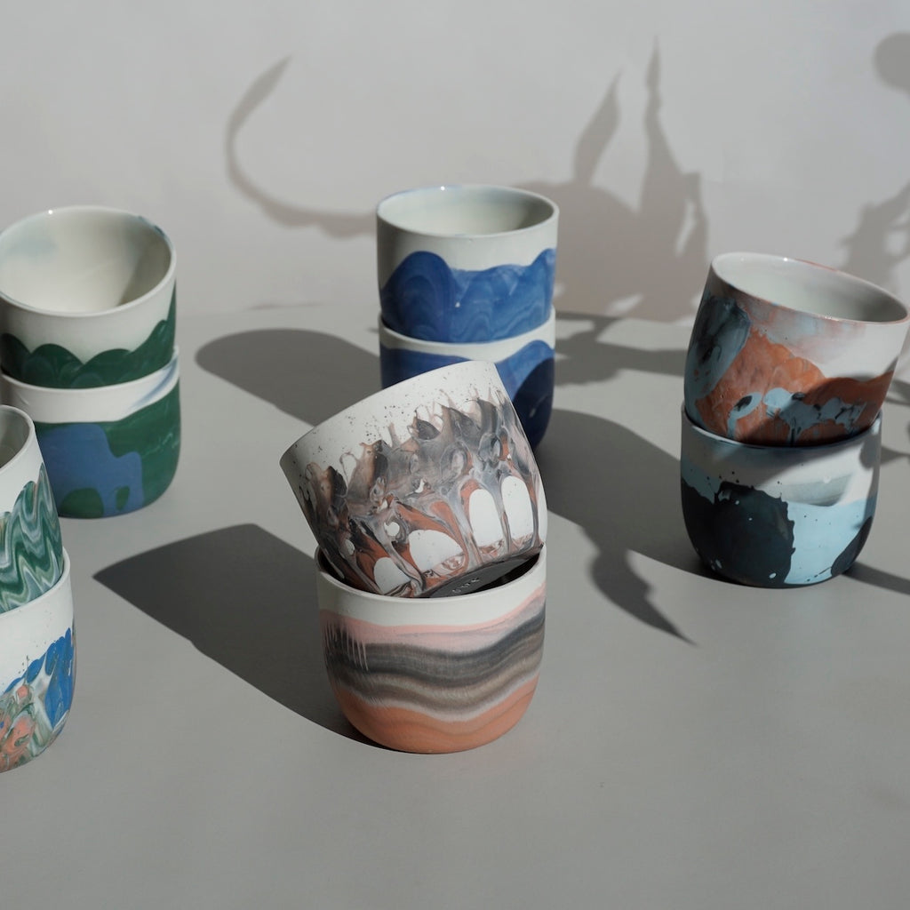 five pairs of porcelain coffee cups by JDP ceramics on a table in the sunshine.