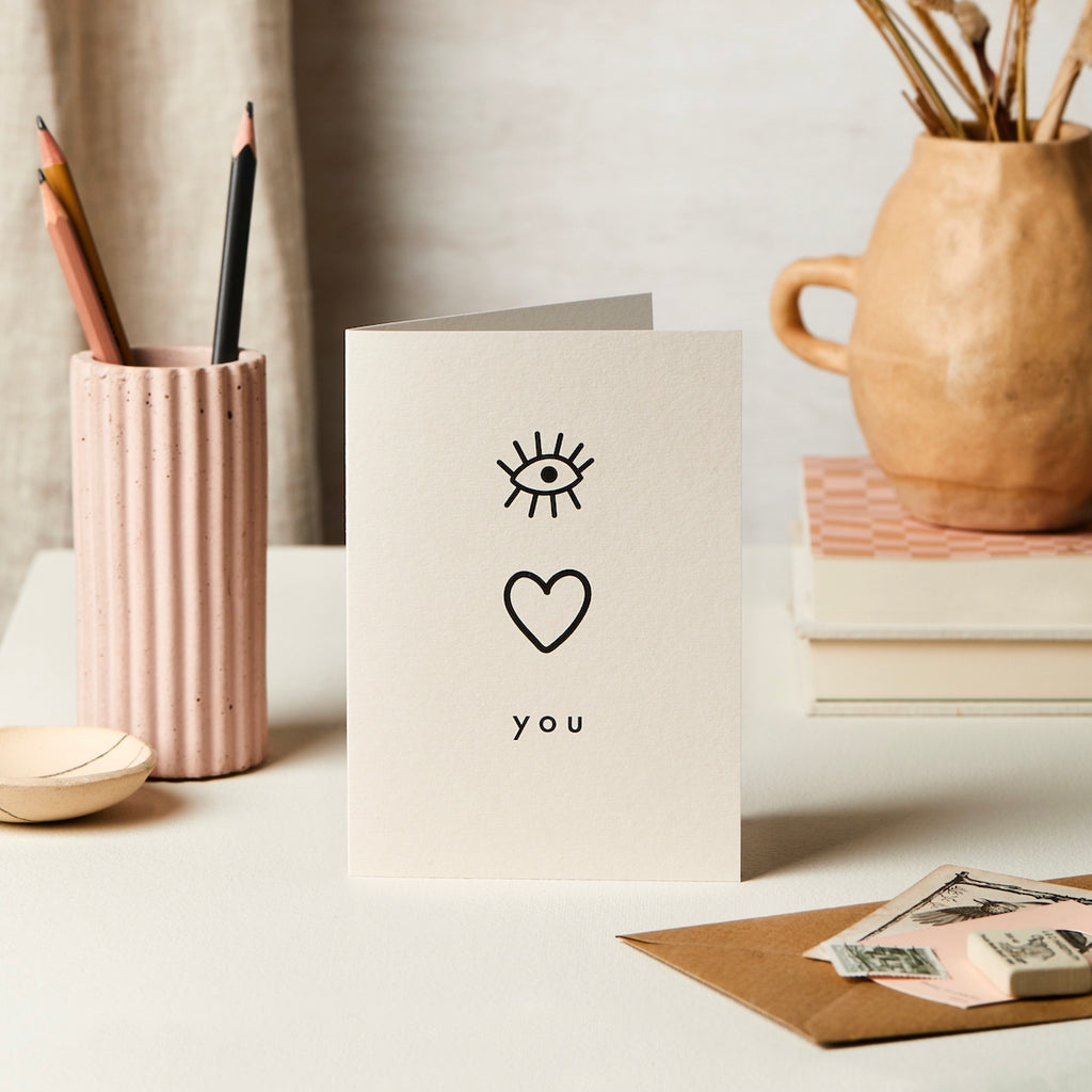 a card on a table with I love you written in symbols to represent each letter.