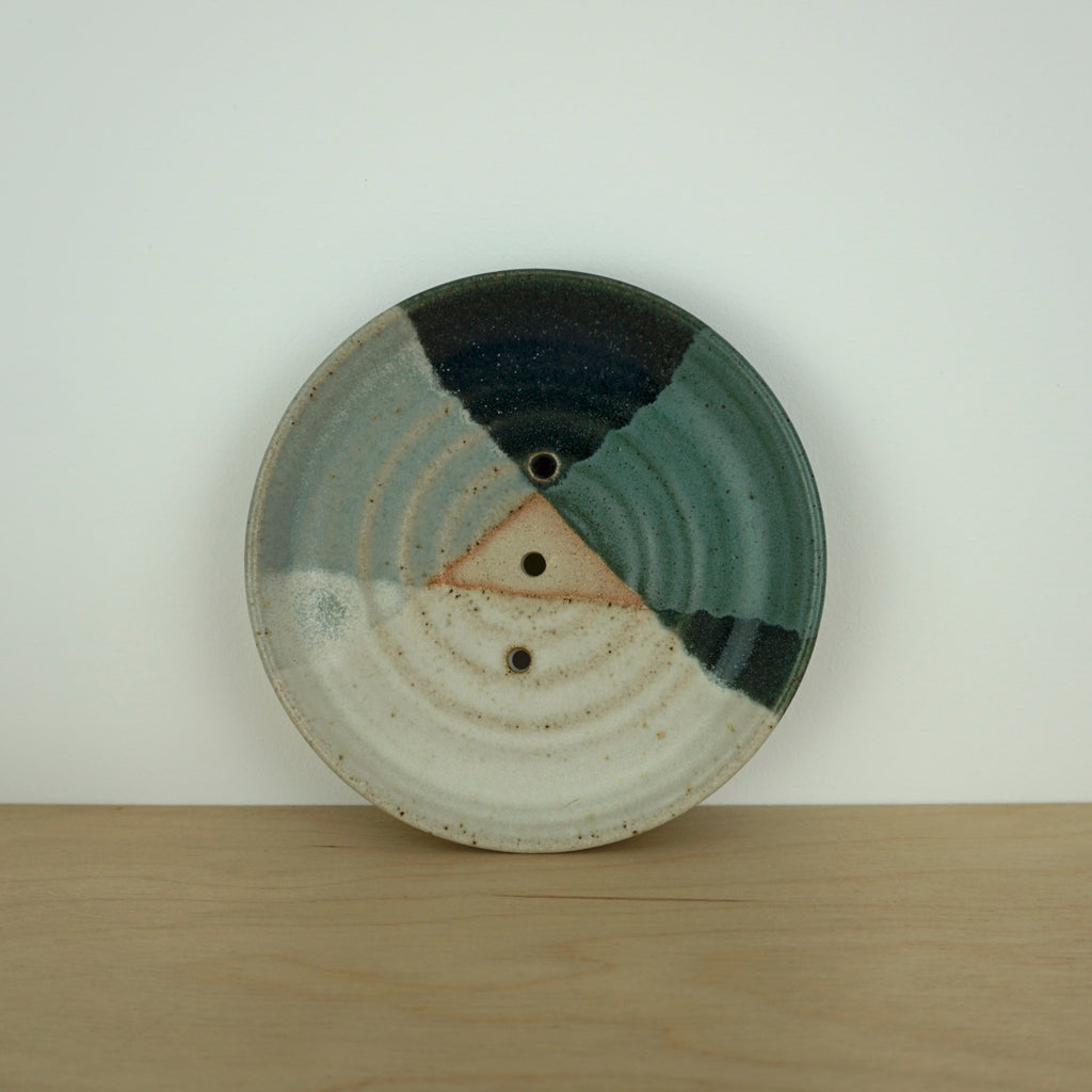 a soap dish with three colours on the glaze on a pale table.