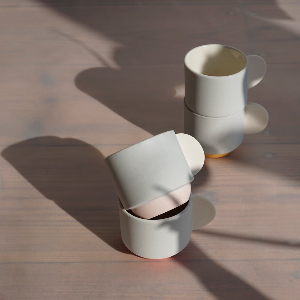 four espresso cups stacked in two piles in the sunshine. 
