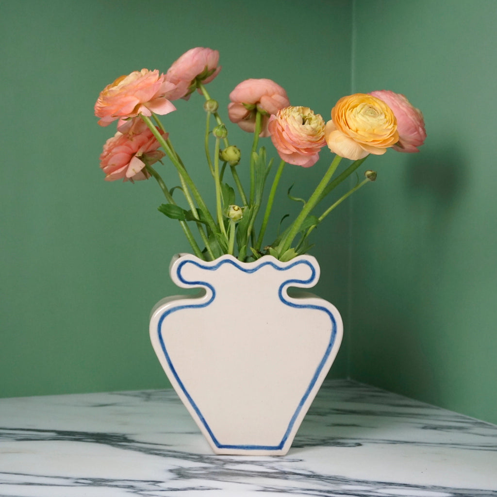 white stoneware vase with a blue outline and pinky yellow flowers. 