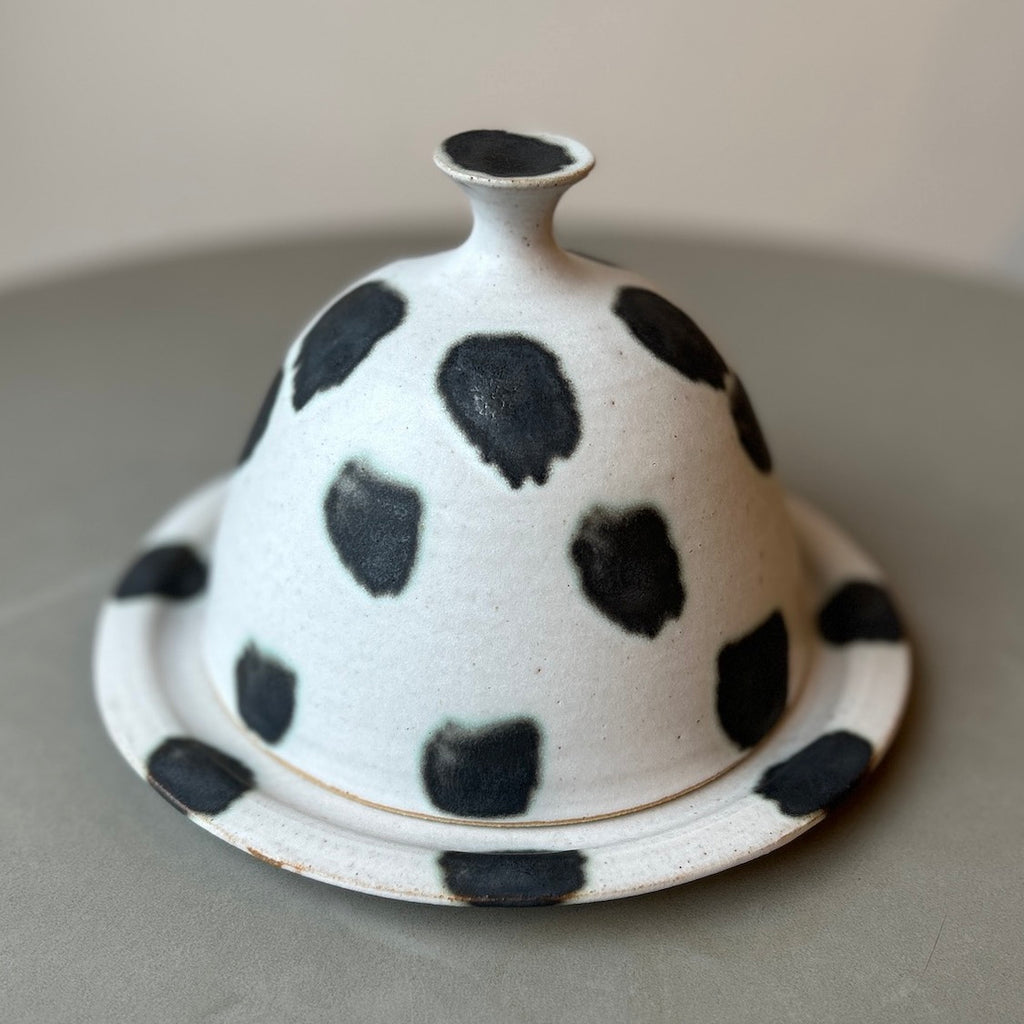 a white butter dish with black splodges by maker Cara Guthrie. 