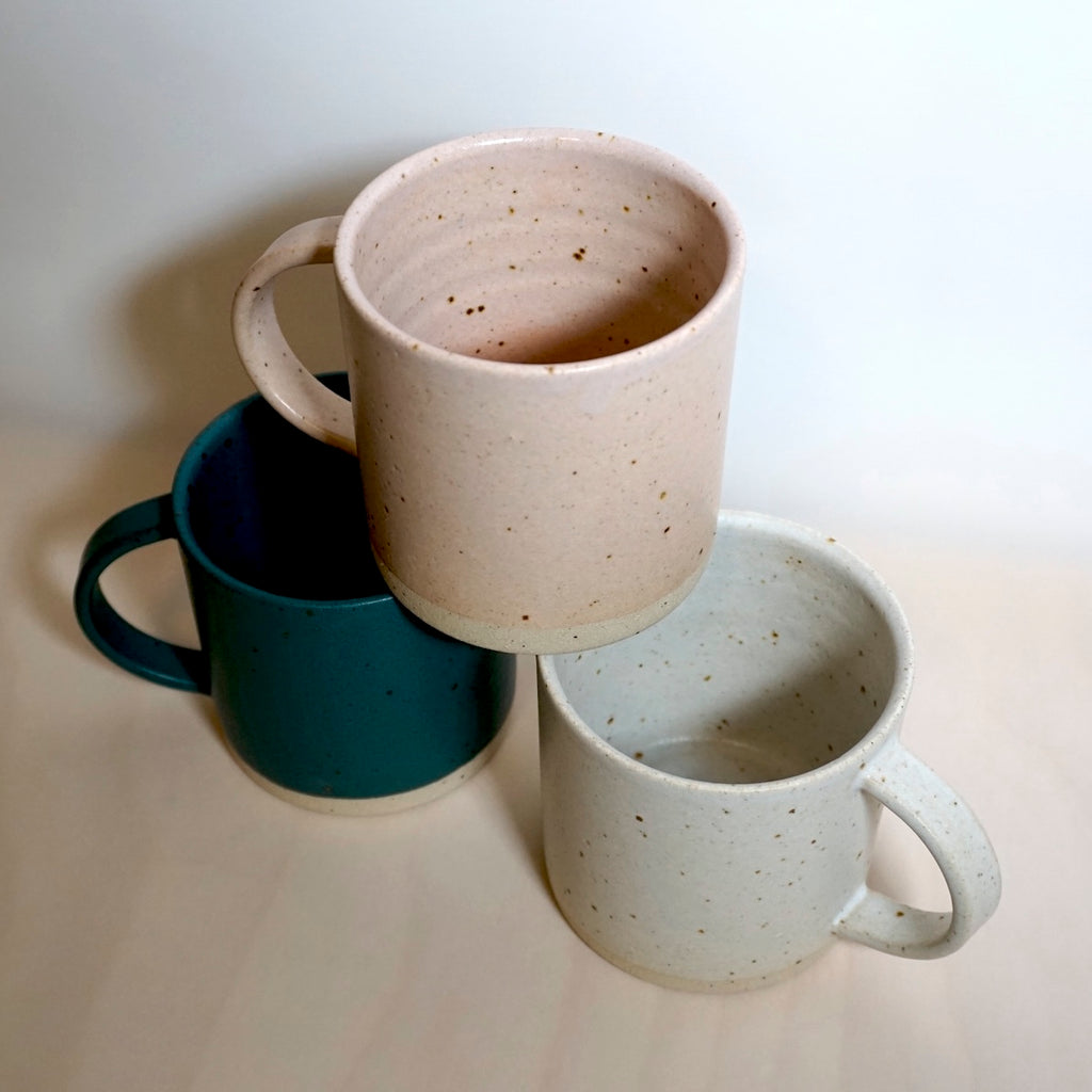 a pink, green and white handmade mug stacked in a tower. 