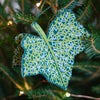 Decorative leaf ornament with intricate pattern hanging on a Christmas tree. East End Press | Shop Fodder