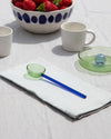 Ceramic mugs, a bowl with strawberries, and glassware on a white surface