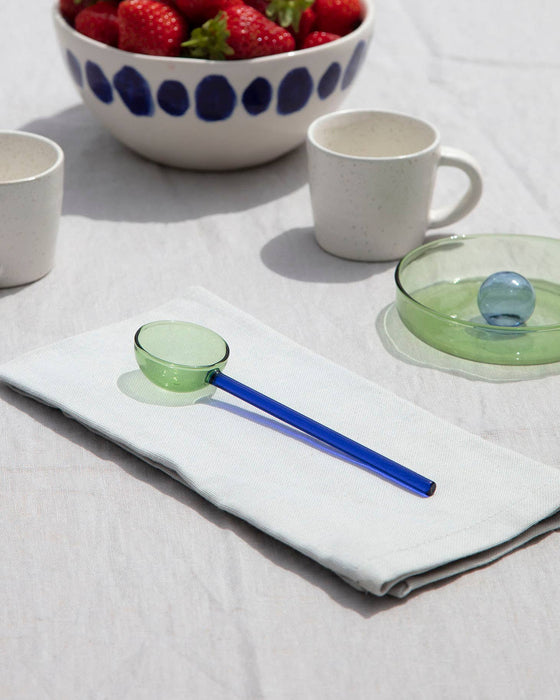 Ceramic mugs, a bowl with strawberries, and glassware on a white surface