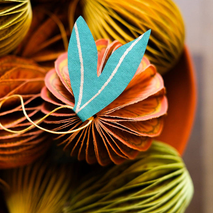 Decorative yarn balls with a central blue leaf-shaped object on a blurred background | East End Press | Shop Fodder