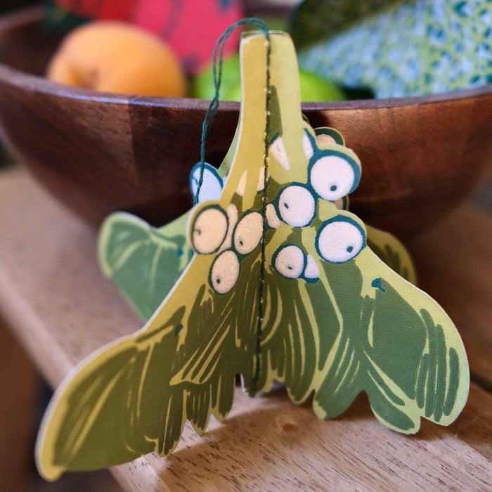 Decorative mistletoe ornaments on a wooden surface with a blurred background. East End Press | Shop Fodder