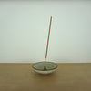 a simple and elegant incense holder with a stick of incense on a table. 