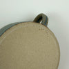 close up detail of the base of a handmade mug with the makers mark of AkU Ceramics. 