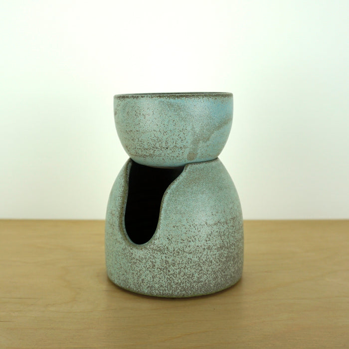 handmade oil burner sitting on a birch ply table with a white background.