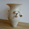 Beige ceramic vase with decorative bows on a wooden surface. Amelia Christoffers | Shop Fodder