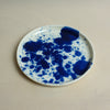 Ceramic plate with blue splatter design on a beige background. Splatter Saucer | Anna Jones Ceramics | Shop Fodder