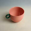 Pink cup with a green handle on a light gray background. Syros Mug | Anna Jones Ceramics | Shop Fodder