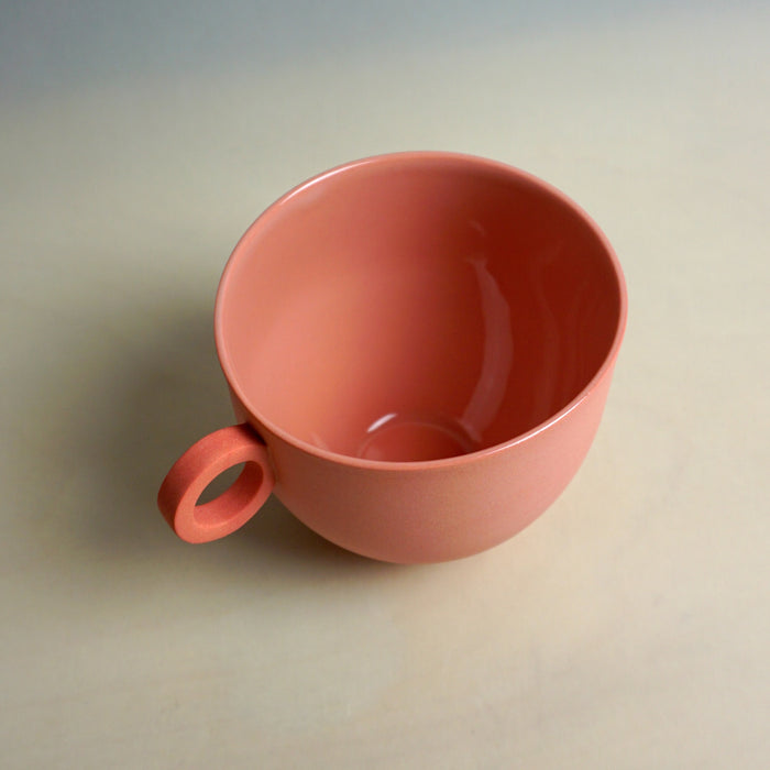Red ceramic mug on a beige background. Syros Mug | Anna Jones Ceramics | Shop Fodder