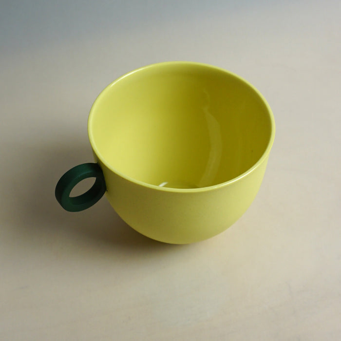 Yellow cup with a green handle on a light gray background. Syros Mug | Anna Jones Ceramics | Shop Fodder