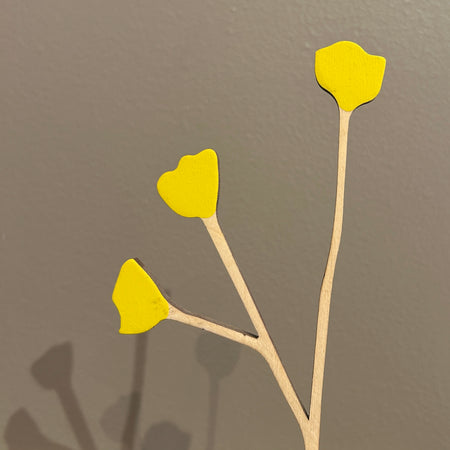 Yellow artificial flowers on thin stems against a gray background. Anna Wiscombe | Shop Fodder