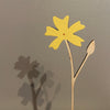 Yellow paper flower with a brown stem on a gray background. Anna Wiscombe | Shop Fodder