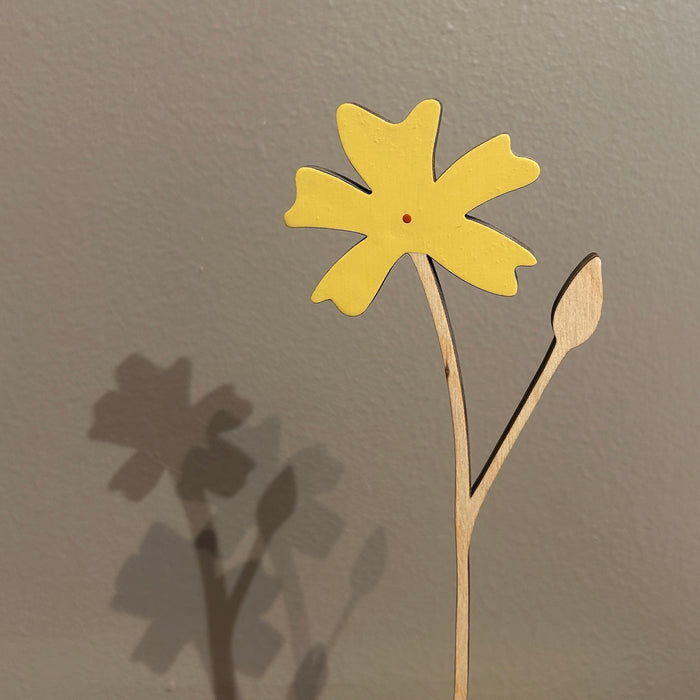 Yellow paper flower with a brown stem on a gray background. Anna Wiscombe | Shop Fodder