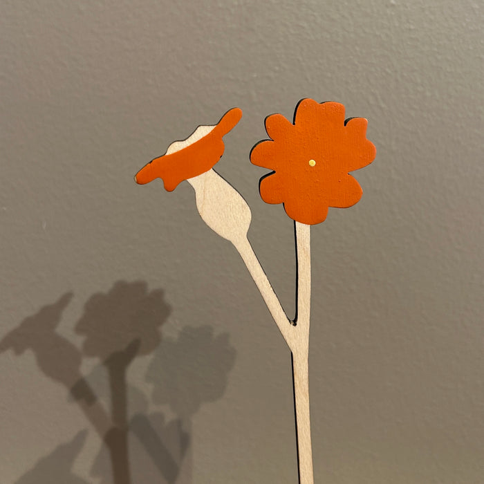 Two orange paper flowers on sticks against a gray background. Anna Wiscombe | Shop Fodder