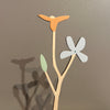 Decorative wall art with a branch, leaves, and a flower on a plain background. Anna Wiscombe | Shop Fodder
