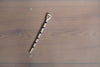 a ceramic salt spoon lying on a table in the sunshine. it has black stripes and a face painted on the end. 
