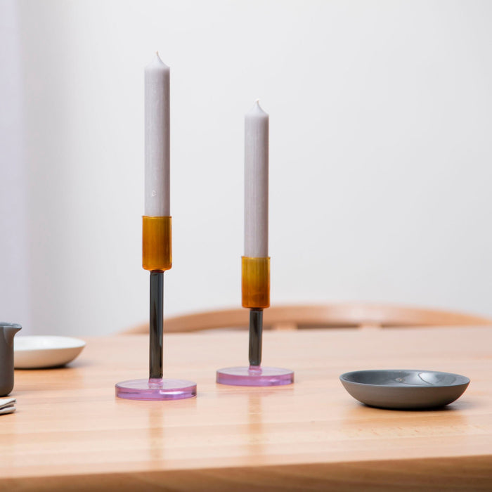 candlestick holders on a table with a jug and a dish. 