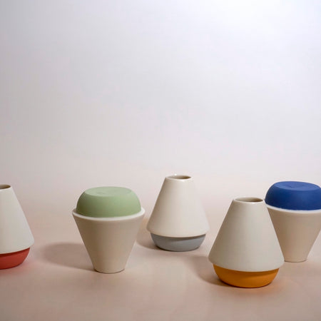 five colourful candlestick holders. all with white bodies and then different coloured bases.