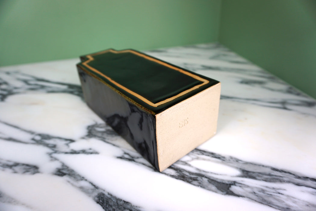 deep glossy black vase lying on a marble table showing the makers mark on the bottom. 