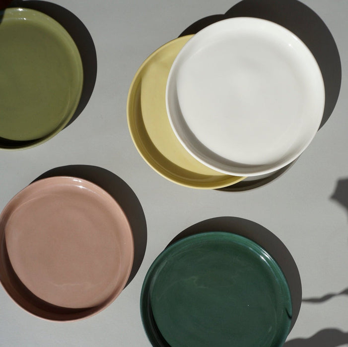 handmade ceramic plates in different colours taken from above. 