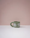 Green ceramic mug with white text on a pink background. Portrait Mug | Brutes London | Handmade Ceramics | Fodder