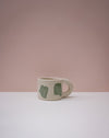 White mug with green designs on a pink background. Portrait Mug | Brutes London | Handmade Ceramics | Fodder