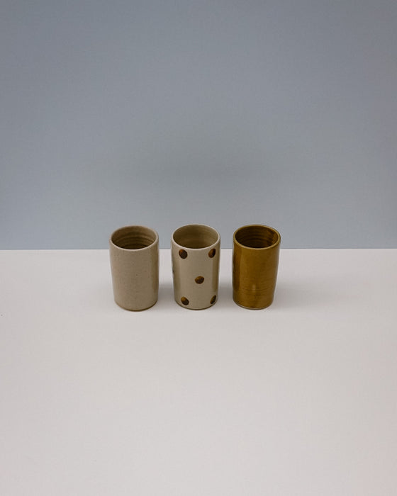 Three ceramic cups with different textures on a white surface and gray background. Ceramic Water cup by Cara Guthrie - handmade stoneware - Fodder