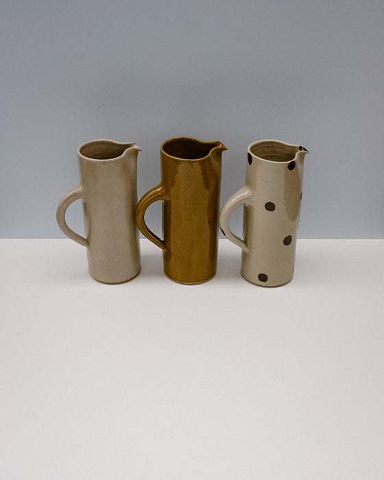 Three ceramic pitchers with different designs on a white surface and gray background - Water jug by Cara Guthrie - handmade stoneware - Fodder