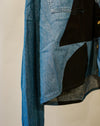 A close-up of a patchwork denim jacket featuring blue and black fabric panels, with a visible button closure and pocket detail. Caroline Dickinson Shirt | Fodder