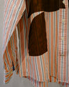 A close-up of a striped button-up shirt with orange, white, black, and thin red vertical stripes, featuring a large brown patch on the chest and a striped sleeve. Caroline Dickinson Shirt | Fodder
