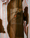 A close-up of a brown corduroy vest layered over a pink, white, and blue striped button-down shirt. The vest features a chest pocket with white contrast stitching and a small orange embroidered sail logo. Caroline Dickinson Shirt | Fodder