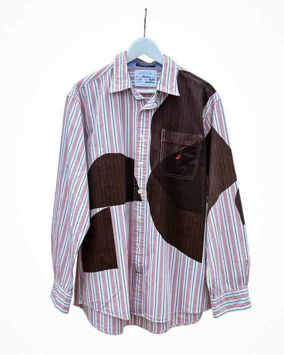 A long-sleeve button-up shirt hanging on a white hanger against a white background. The shirt features a pink, white, and blue striped base with large dark brown patchwork panels on the front and chest pocket. Caroline Dickinson Shirt | Fodder