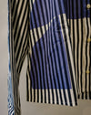 Close-up of a striped button-up shirt with navy, blue, cream, and black vertical stripes, featuring a pocket and light-colored buttons. Caroline Dickinson Shirt | Fodder