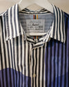 A close-up of a Caroline Dickinson shirt on a white hanger, featuring vertical stripes in navy blue, white, and black, with a blue and white abstract pattern on the lower half. Caroline Dickinson Shirt | Fodder