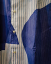 Close-up of a button-front shirt with vertical light stripes on one side and large solid dark blue fabric panels on the other, with cream buttons. Caroline Dickinson Shirt | Fodder