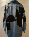 A long-sleeve denim shirt shown from the back, featuring a large abstract black geometric patchwork pattern over a light blue denim base. Caroline Dickinson Shirt | Fodder