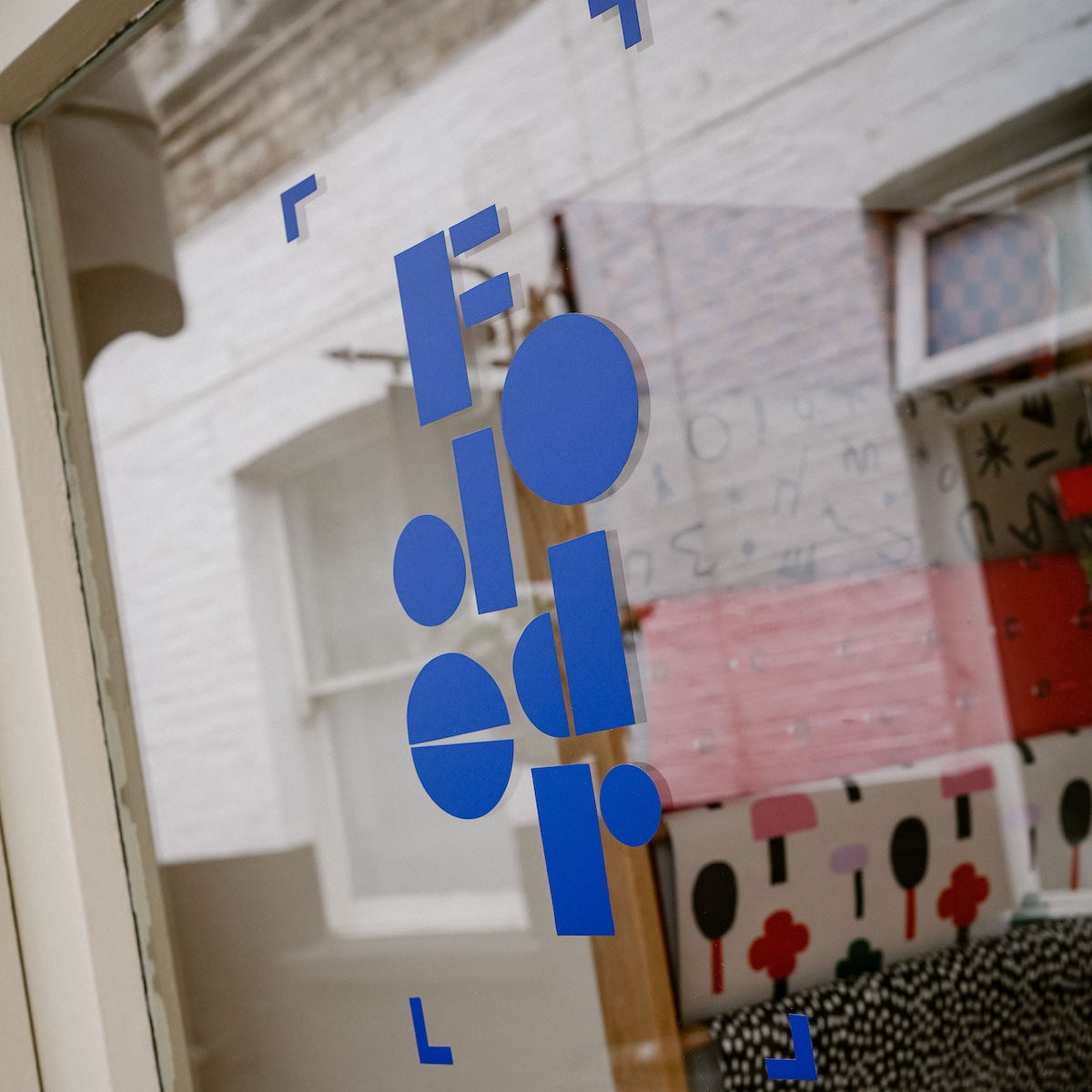 Blue 'Fodder' logo on a glass door with a blurred interior background | Fodder, Hampstead, NW3