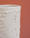 A close-up of a textured, off-white ceramic pot or vase with a rough, hand-painted plaster-like finish, set against a solid terracotta background.  Brutes Ceramics | Hope Collection | Shop Fodder