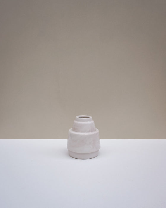 A small ceramic vase with a textured, matte finish in a light off-white color, set on a white surface against a neutral beige background. Emma Johnson Ceramics | Fodder | Hope Collection