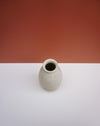 A small speckled ceramic vase with a wide opening, standing on a white surface against a terracotta-colored background.  KJA Studio Ceramics | Hope Collection | Shop Fodder