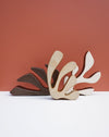 Three abstract leaf-shaped wall art sculptures in beige, brown, and white, arranged in a fan shape against a terracotta background and white surface. Studio ERS Ceramics | Hope Collection | Shop Fodder