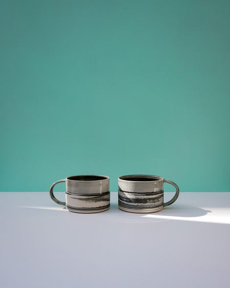 Two ceramic mugs on a light surface with a teal background. Janne Meijer Ceramics | Shop Fodder