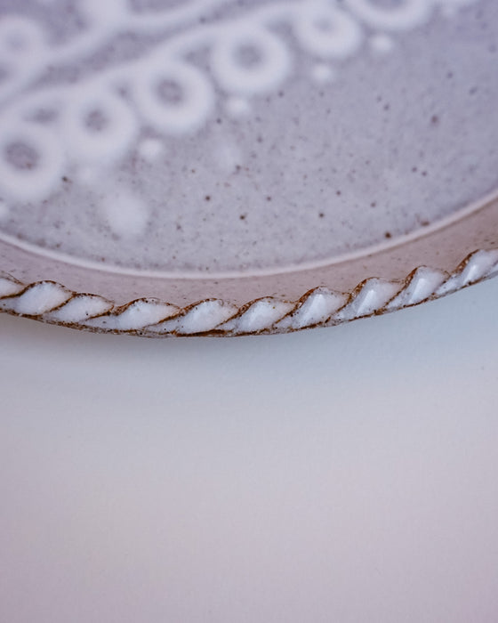 Close up of trailed cream slip pattern and pie crust rim