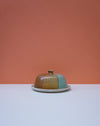 Ceramic butter dish with a lid on a white surface against an orange background. Liz Vidal Ceramics | Shop Fodder